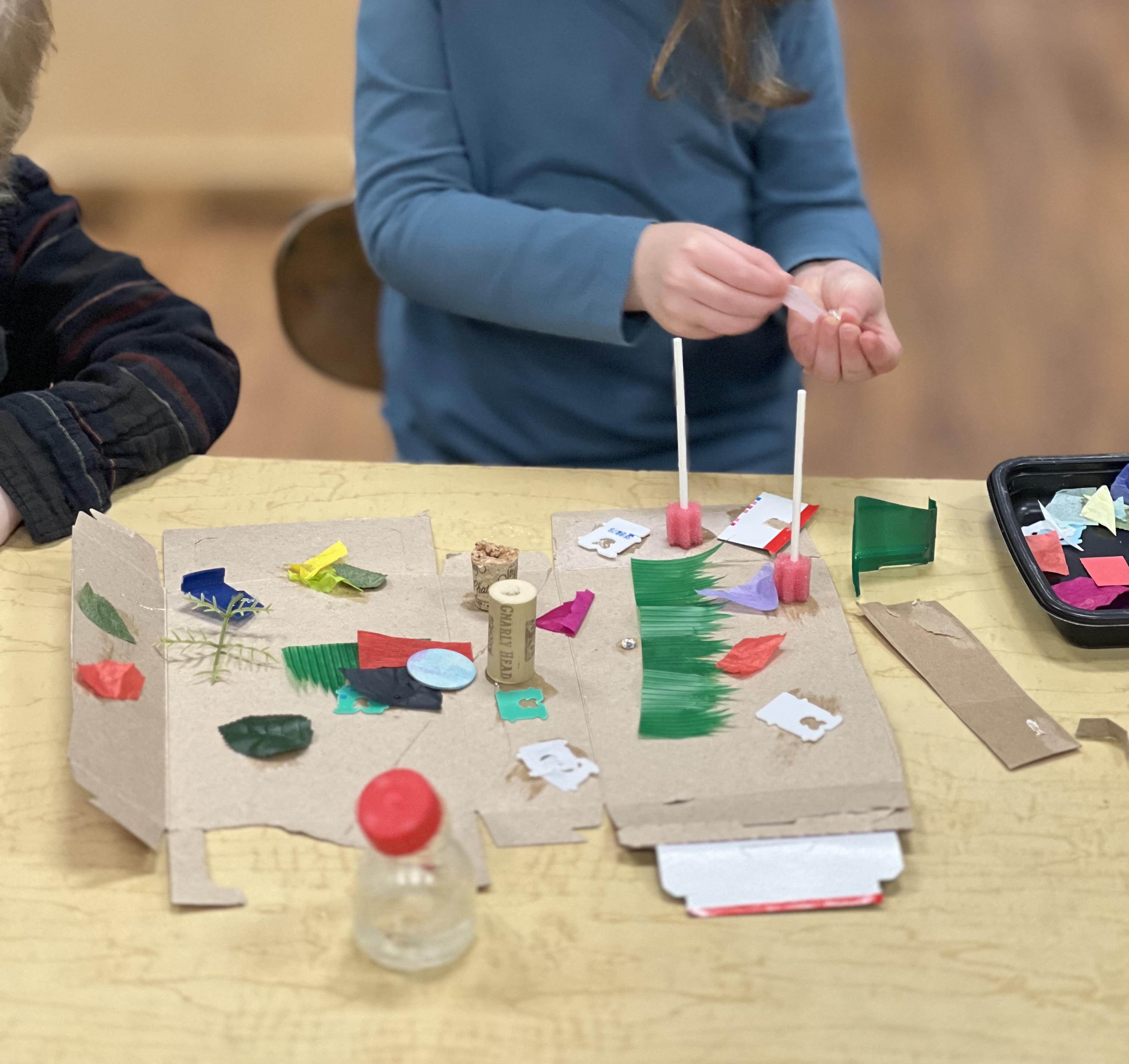 Preschool-aged child making a sculpture with recycled materials.