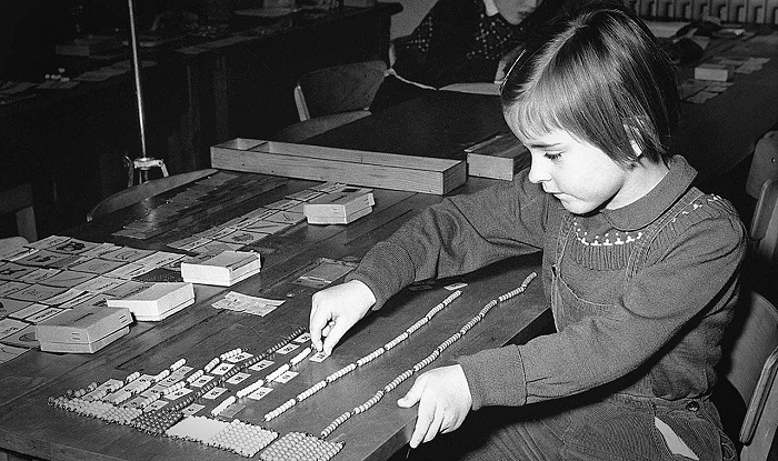 Historic photograph of preschool-aged girl using bead chains.