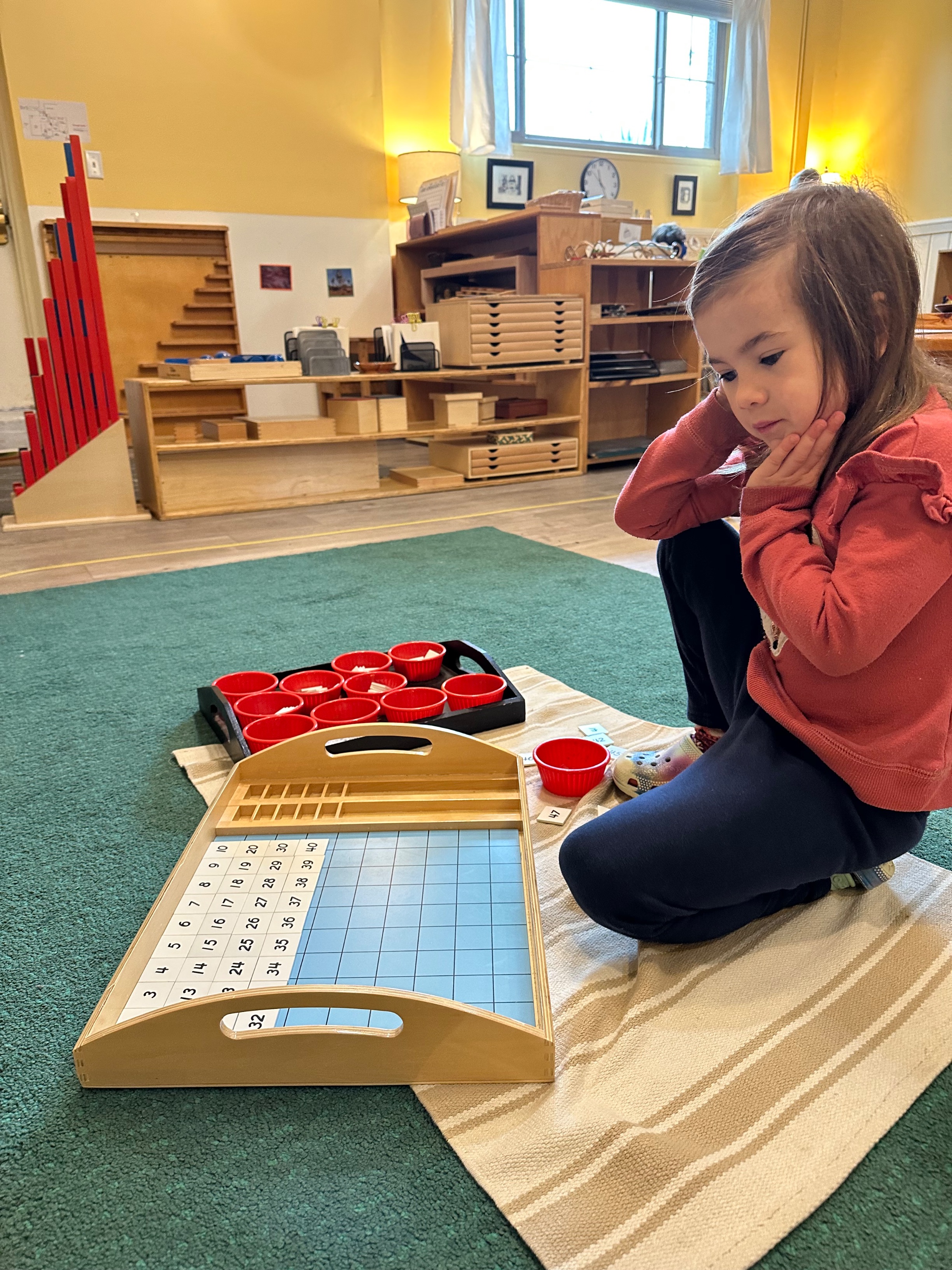 Preschool-aged girl sitting on floor using the hundreds board