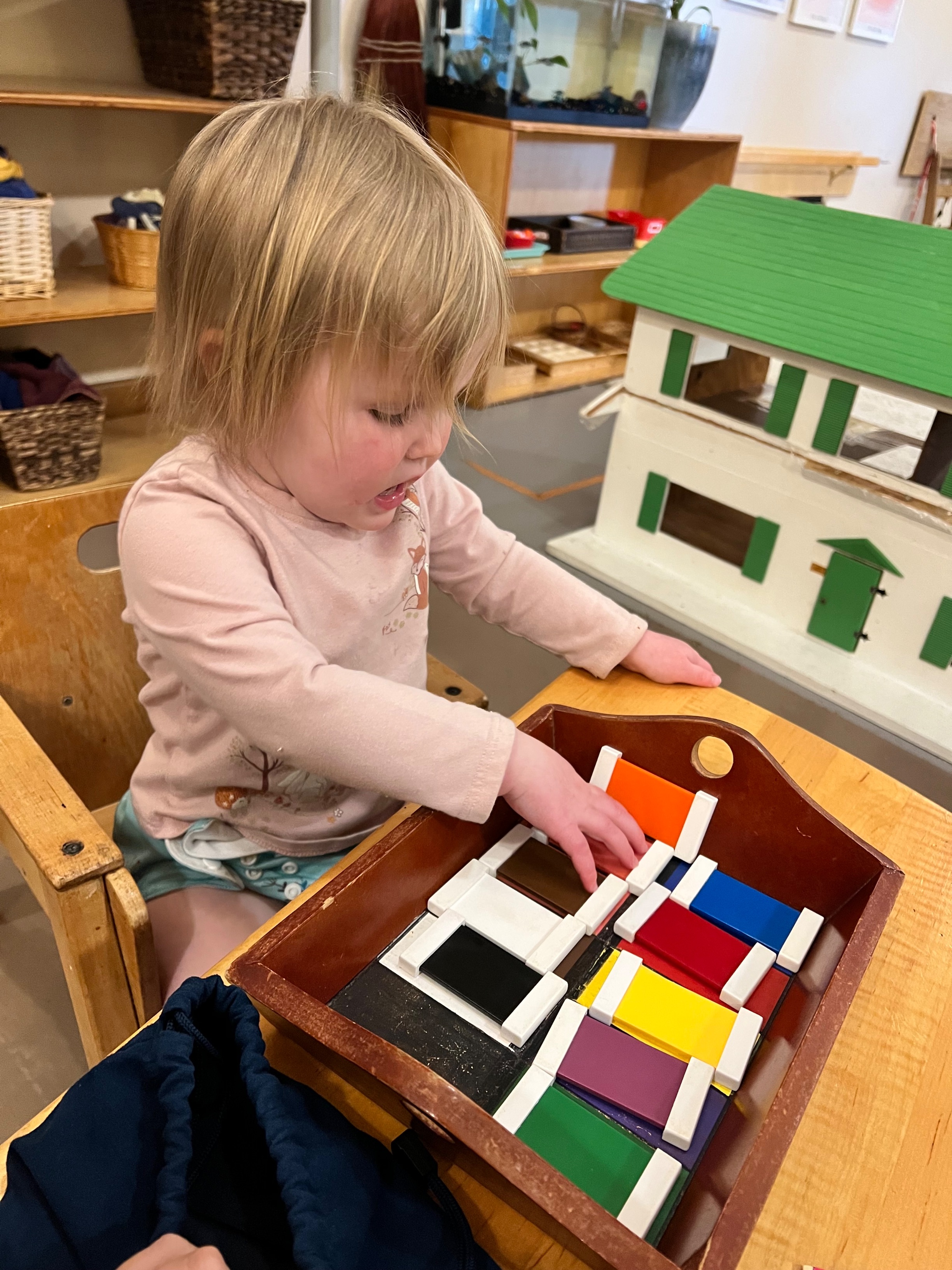 A toddler girl uses Montessori color tablets.