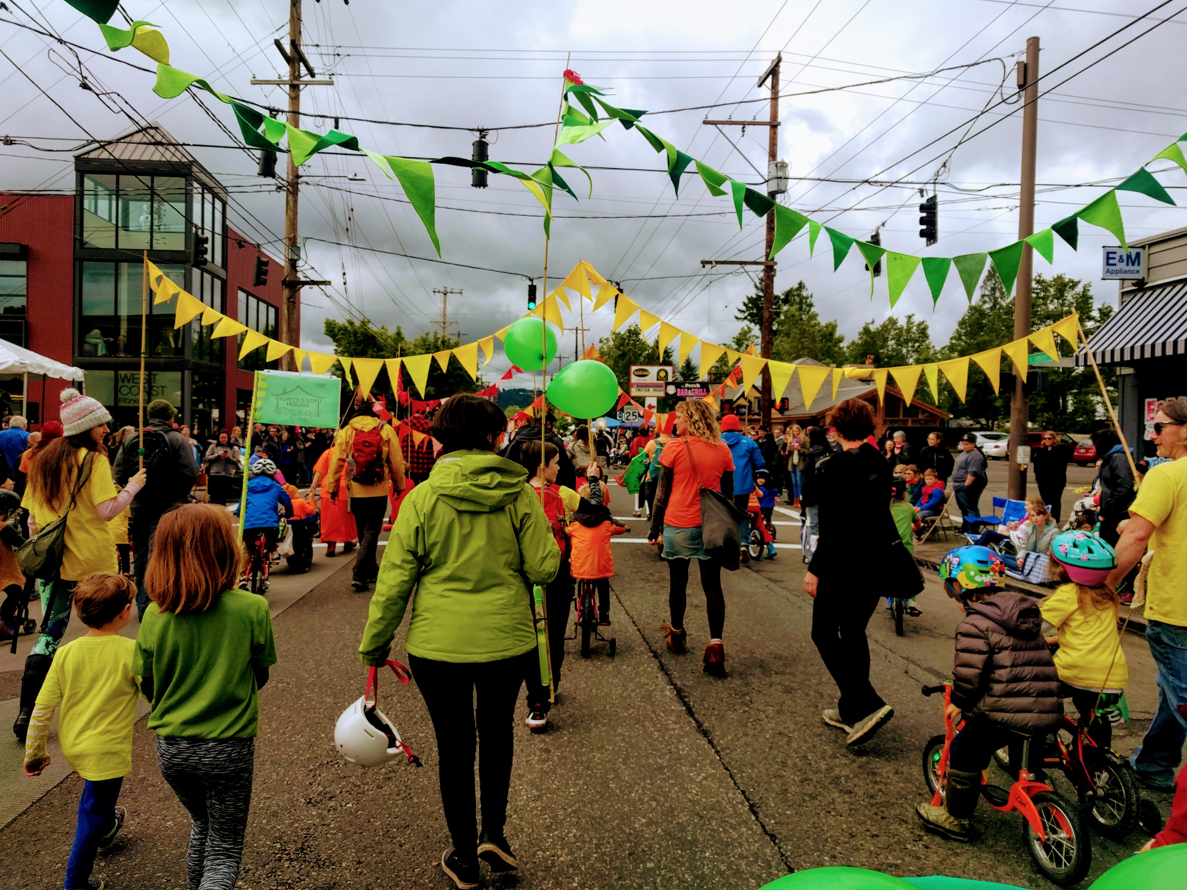 Parents and children of The Montessori House marching in the parade, holding banners and balloons.