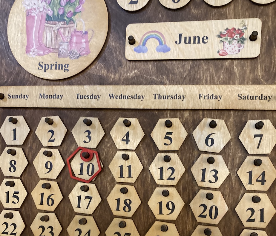 Calendar made of wood with moveable pieces for dates, month, and season.